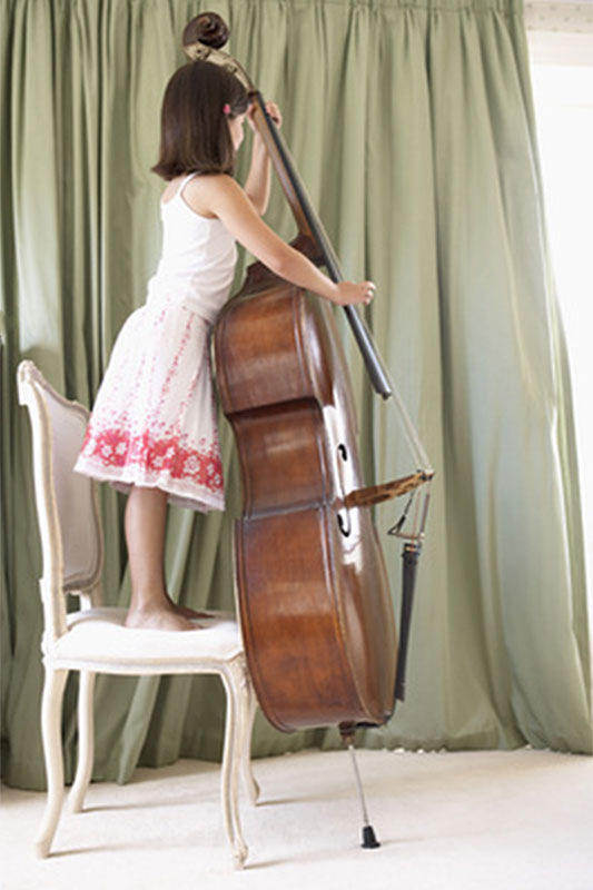Kind auf Stuhl spielt Cello